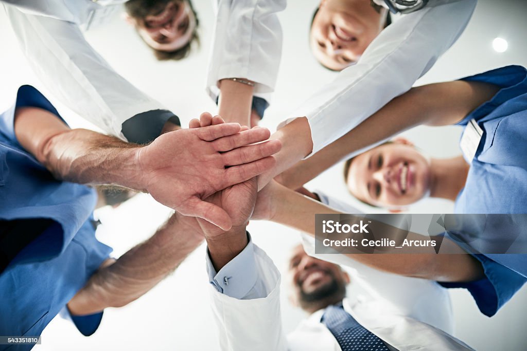 Shot of a diverse team of doctors joining their hands together in unity